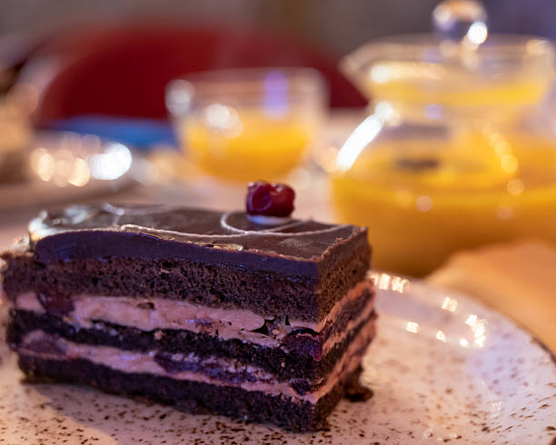 istock Chocolate cherry cake slice with blurred tea set in background 2225627719