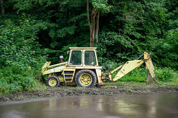 Tractor excavator against the background of spring flowers in the field. Preparing fields for sowing.