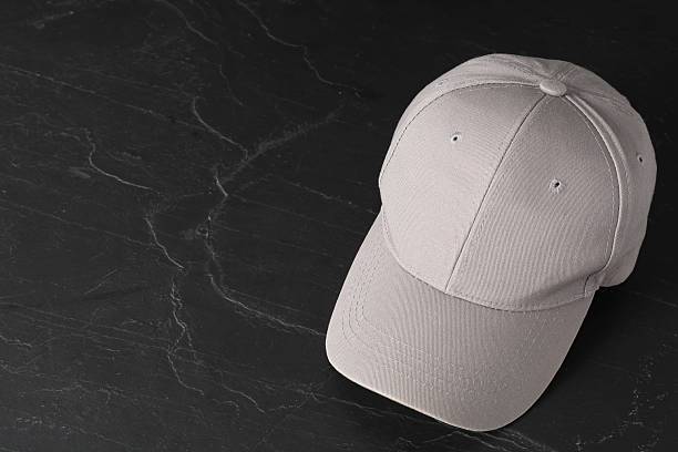 Stylish baseball cap on dark textured table. Mockup for design