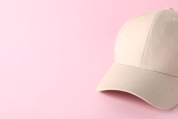 Portrait of beautiful young woman wearing grey jumper, nerd glasses and pink baseball cap, looking at camera with disappointed facial expression. Studio shot, white background.