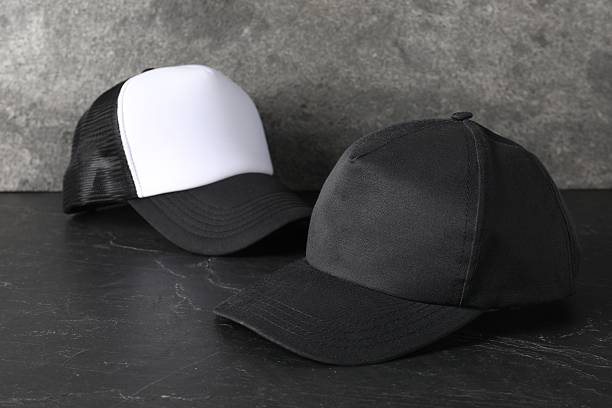 istock Stylish baseball caps on dark textured table. Mockup for design 2225632633