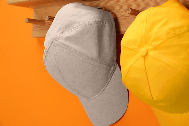 istock Stylish baseball caps on orange wall, closeup. Mockup for design 2225632651