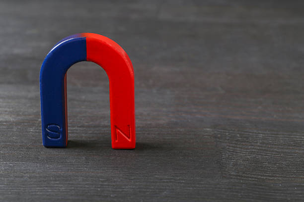One horseshoe magnet on black wooden table, space for text