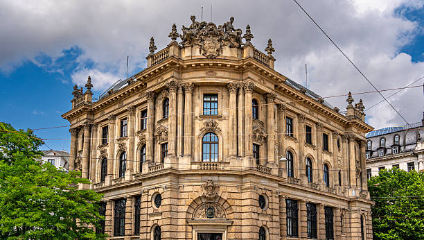 istock Baroque Architecture In Munich: Ornate Historic Building With Sculpted Facade, Arched Windows, Decorative Columns, And Stone Details Under Blue Sky With Clouds In Vibrant Urban Cityscape 2225635594