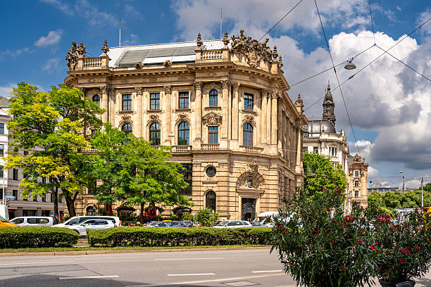 istock Baroque Architecture In Munich: Ornate Historic Building With Sculpted Facade, Arched Windows, Decorative Columns, And Stone Details Under Blue Sky With Clouds In Vibrant Urban Cityscape 2225636570