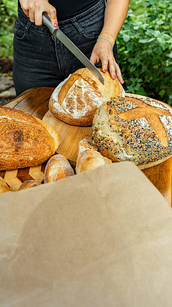 istock Baker slicing freshly baked bread on wooden board 2225638816