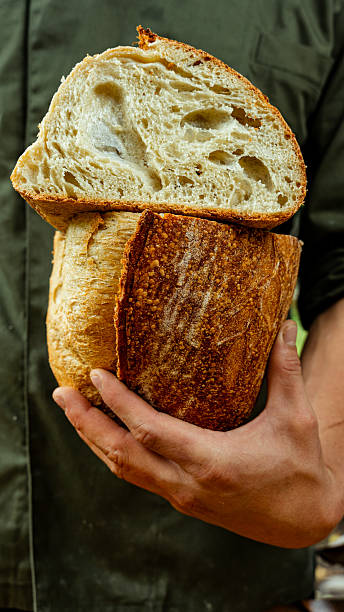 Baker holding two freshly baked loaves of bread