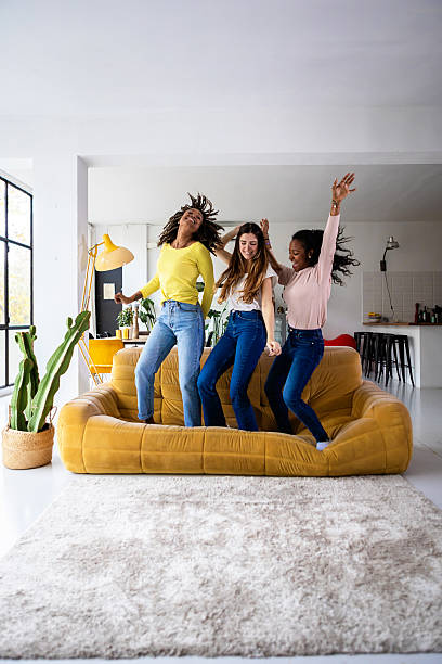 istock Three happy young girls dancing on sofa at home 2225640006