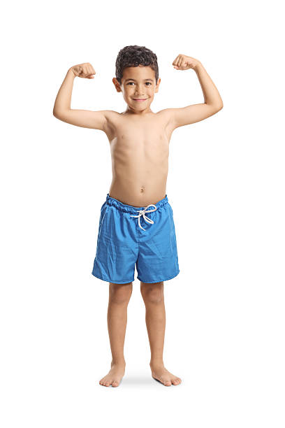 Kid in swimming shorts showing arm muscles isolated on white background