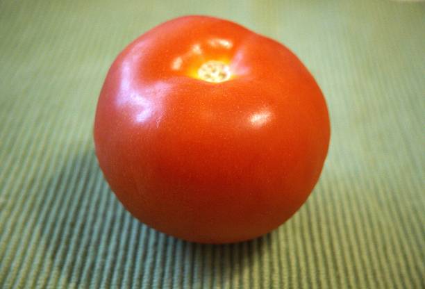 istock One whole red tomato with green background. 2225642015