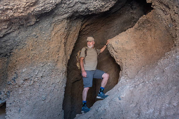 istock Portrait of a confident mature hiker with a backpack standing inside a rugged rock cave. Exploration concept. 2225643013