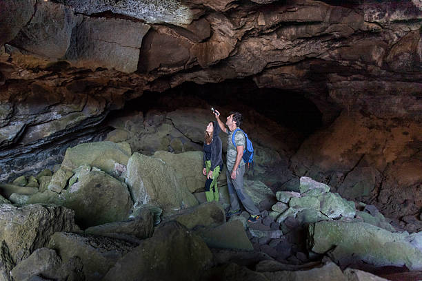 istock Couple with flashlight exploring a dark cave during a hike. Travel concept 2225643086