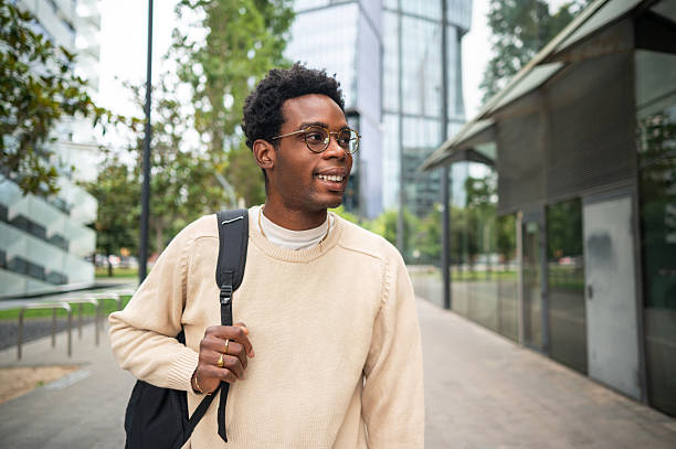 istock Smiling young man walking in the city with backpack 2225643574