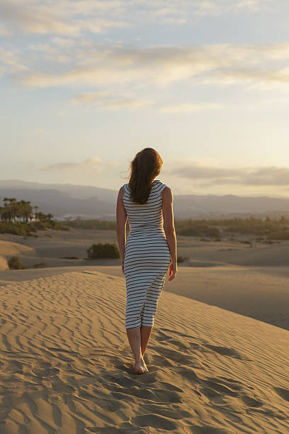 istock Woman walking on sand dunes at sunset 2225648744