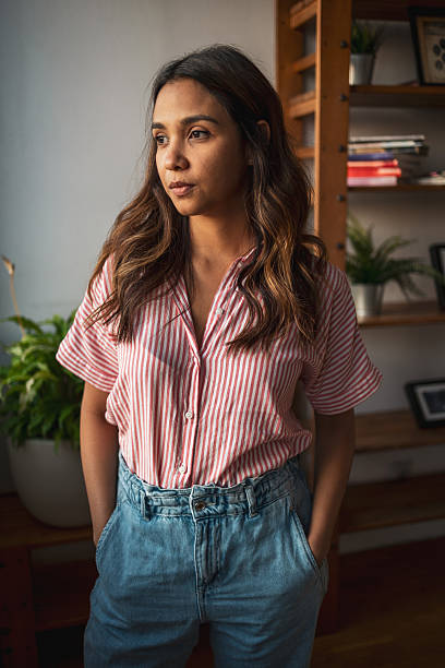istock Young woman looking away while posing with hands in pockets 2225649860