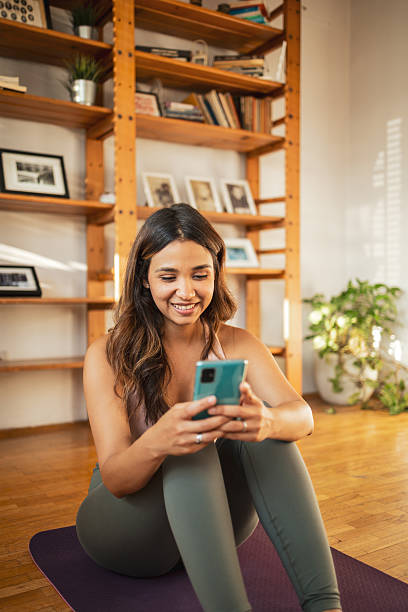 istock Young woman using smartphone while relaxing on yoga mat at home 2225650244