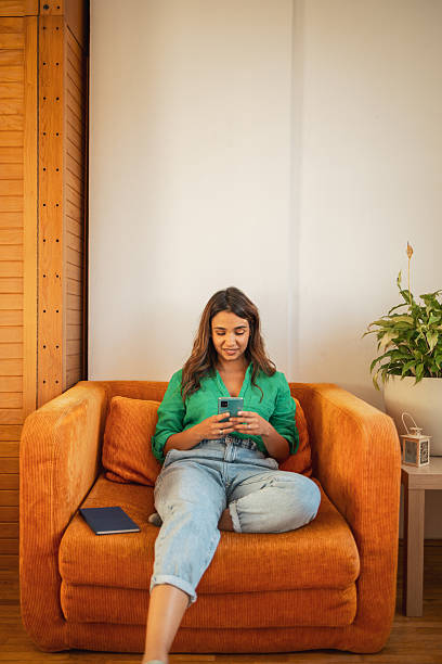 istock Young woman relaxing on sofa using smartphone at home 2225650251