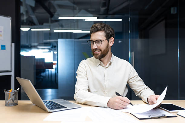 istock Smiling young businessman working in the office with documents, talking on a video call and holding an online conference with partners 2225651466