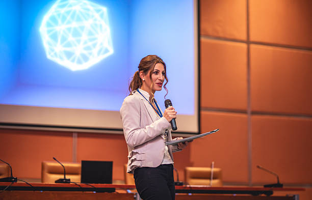 istock Caucasian Businesswoman Presenting at Conference with Microphone and Presentation Screen 2225652633