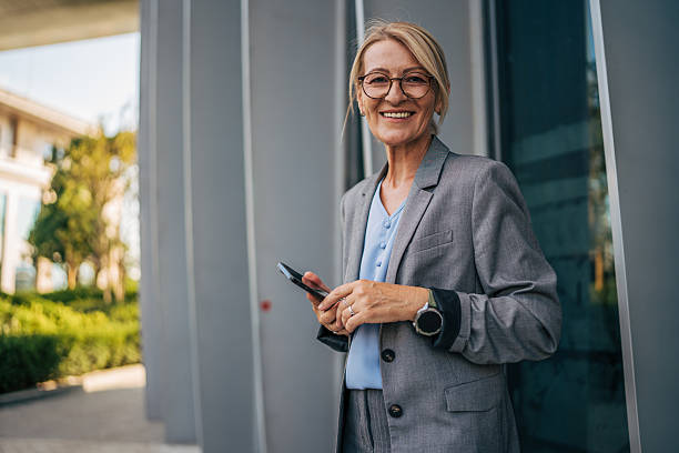 istock Smiling senior businesswoman using smartphone outside office building 2225653975