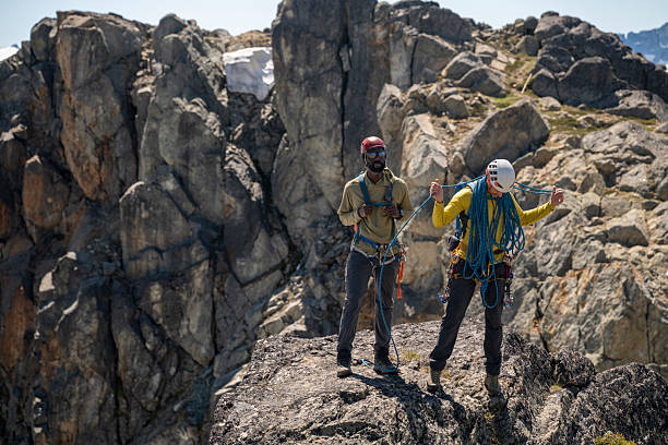 istock Climbing guide prepares rope with client on mountain top 2225667496