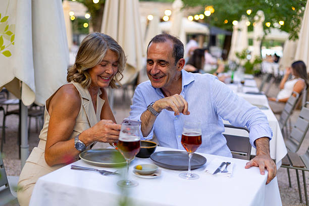 istock Smiling senior couple enjoying dinner and using smartphone at outdoor restaurant 2225673098