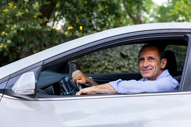 istock Mature man driving a car and smiling at camera 2225673150