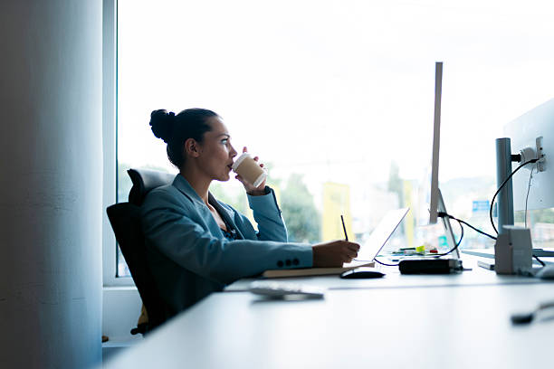 istock Businesswoman drinking coffee while working at her desk 2225675154