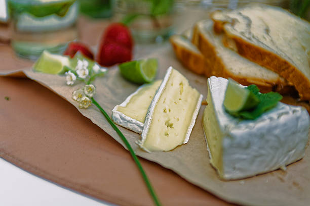 Freshly Baked Bread With Creamy Brie Cheese, Lime, Strawberries, And Slices Of Avocado Laid Out On Parchment For A Light Rustic Snack In A Cozy Atmosphere. Perfect For A Summer Brunch Or Garden Picnic Setting.