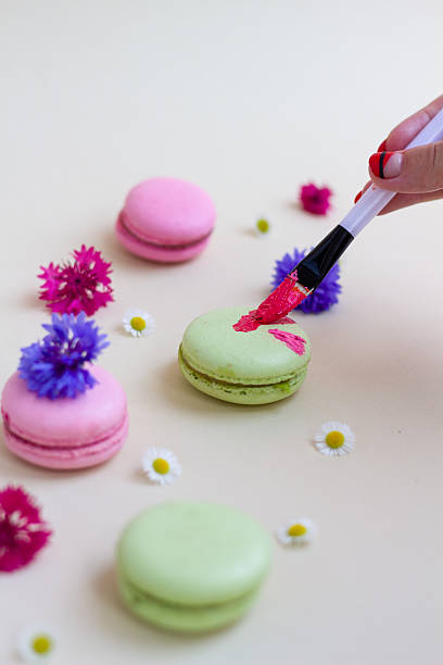 Colorful macarons being creatively painted with red brush strokes