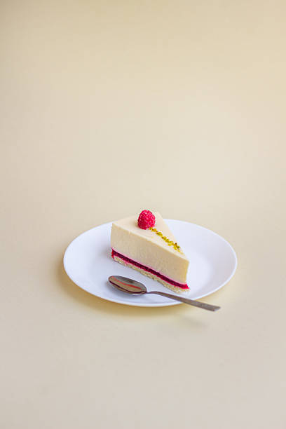 istock A slice of elegant raspberry mousse cake with creamy layers and a delicate topping, served on a white plate with a spoon. 2225688810