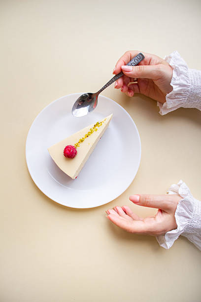 Elegant Woman’s Hands Reaching for a Raspberry Mousse Cake on a White Plate.