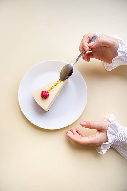 Elegant Woman’s Hands Reaching for a Raspberry Mousse Cake on a White Plate.