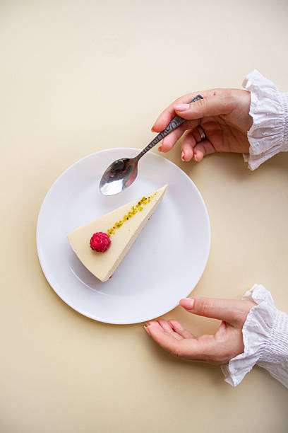 Elegant Woman’s Hands Reaching for a Raspberry Mousse Cake on a White Plate.