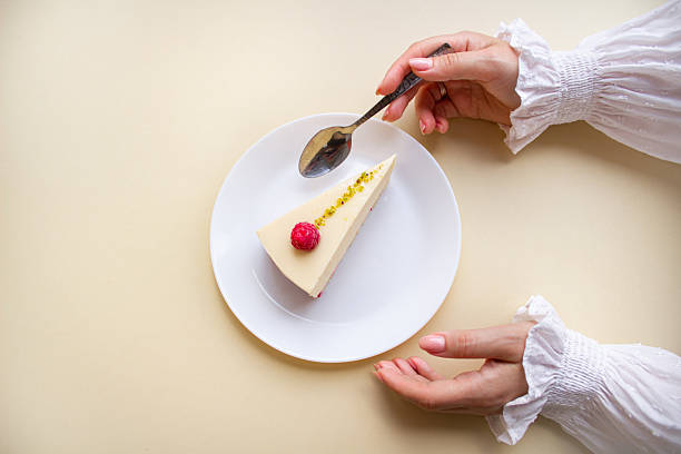 Elegant Woman’s Hands Reaching for a Raspberry Mousse Cake on a White Plate.