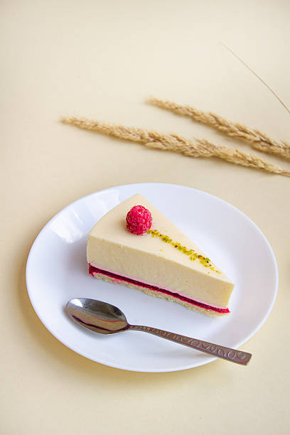 istock A slice of elegant raspberry mousse cake with creamy layers and a delicate topping, served on a white plate with a spoon. 2225688925