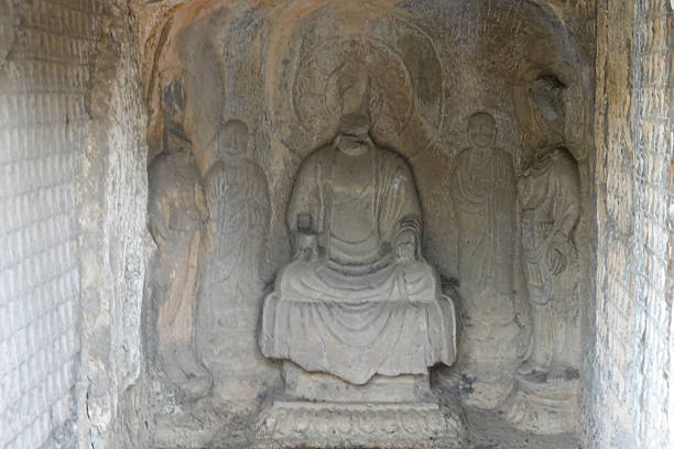 This photograph presents a beautifully preserved statue of a seated Buddha at the Longmen Grottoes. The figure rests on a lotus throne, a symbol of purity and enlightenment, and its face holds an expression of deep serenity and compassion. The craftsmanship is evident in the smooth contours of the body and the graceful fall of the robes. This statue is a classic example of the mature Buddhist sculptural style, designed to inspire a meditative and reverent state in the viewer.