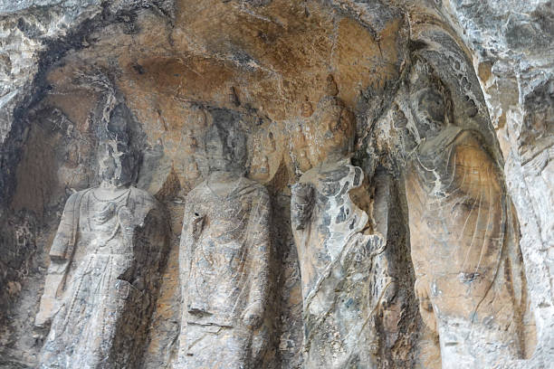 This image documents a group of Buddhist statues in a Longmen grotto that have suffered significant damage, particularly to their heads, which are missing. This type of destruction was common during periods of anti-Buddhist persecution in Chinese history or due to later vandalism and theft. The photograph serves as a stark reminder of the historical vicissitudes the site has faced. The headless figures are a poignant symbol of cultural loss, even as the remaining sculpture testifies to the original artistry.