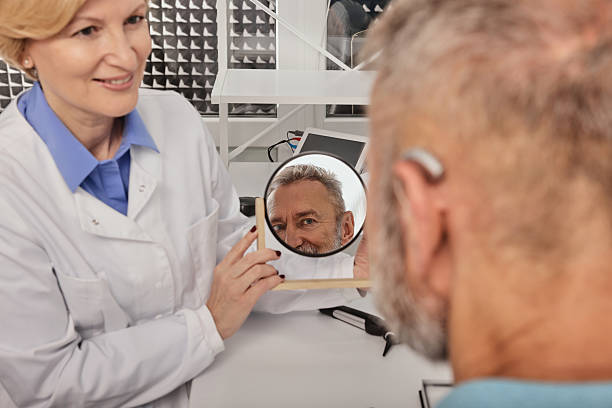 istock Hearing aids and solutions. Audiologist offers BTE hearing aids to man patient with hearing problems for treatment his deafness 2225701192