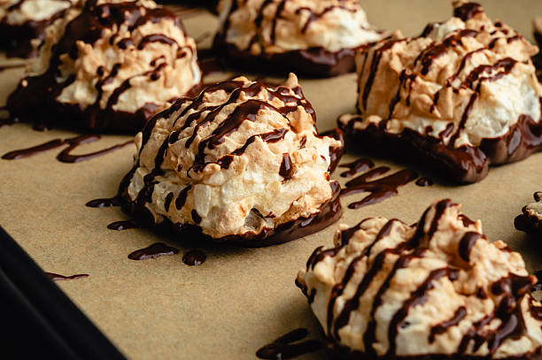 Coconut meringue drop cookies dipped in bittersweet chocolate on parchment paper