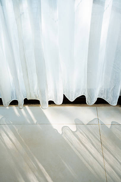 istock Soft sheer white curtains with natural light filtering through, bright airy interior space with reflections on the tiled floor, calm and minimalist home design. 2225704674
