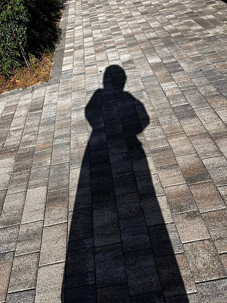istock The silhouette of a person cast on a textured surface, their form slightly distorted by the angle of light. The shadow creates a mysterious and intriguing composition. 2225718814