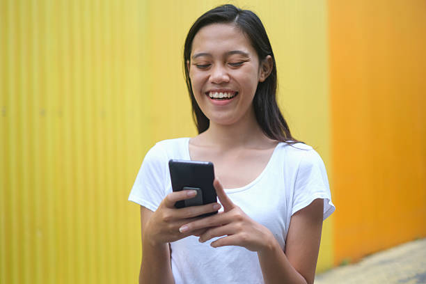 istock Smiling Woman Using Smartphone on Colorful Street 2225722768