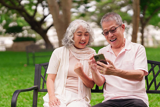 istock Older Asian couple using smartphone happily together outdoors in park enjoying modern retirement lifestyle technology 2225737560