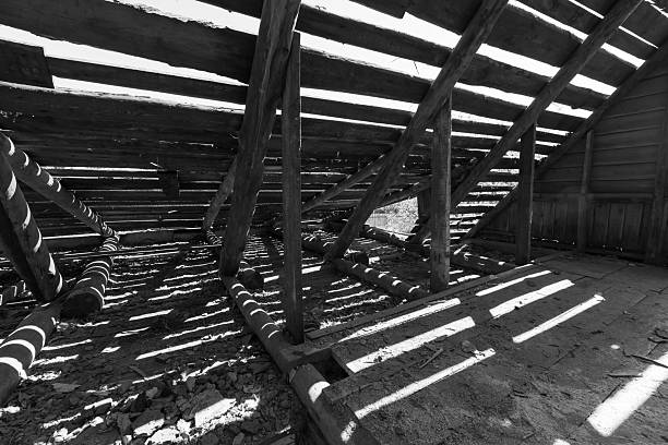 Dark interior view with wooden structure showcasing exposed beams with sunlight creating unique patterns. Abstract black and white background photography