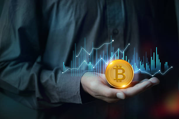 istock A hand holds a Bitcoin in front of a holographic candlestick trading chart, representing cryptocurrency 2225741895