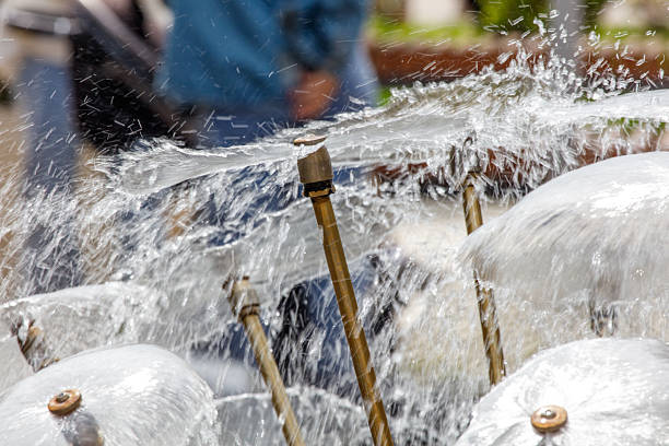A fountain with a person in the background. The water is spraying out of the fountain and the person is holding a camera