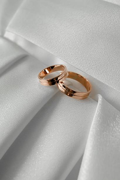 istock Two Gold Wedding Rings on White Fabric Background 2225745234