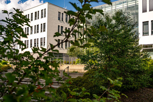 istock Modern Architecture In Freiham Munich Bavaria: Minimalist Building With Geometric Facade, Large Windows, And Small Tree In Courtyard Under Cloudy Sky 2225745890
