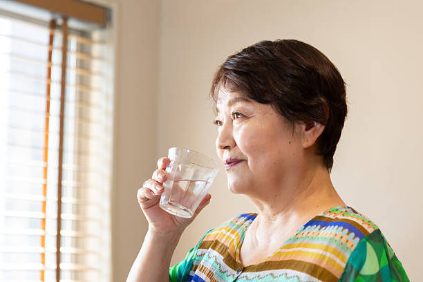 istock A senior woman drinking water in the room. 2225748232